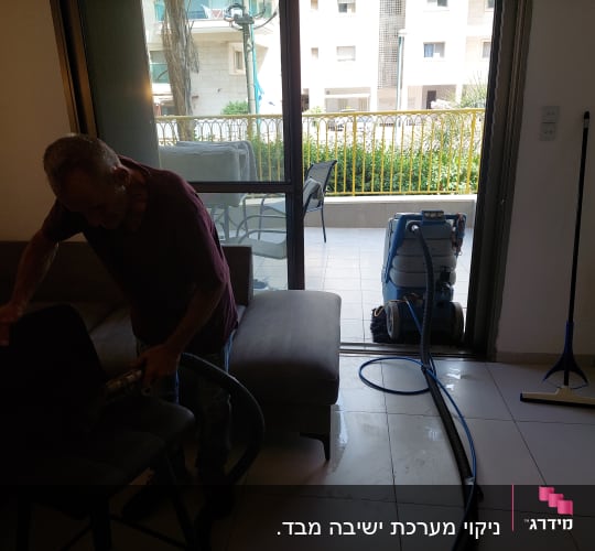 אדם מנקה כיסא עם שואב אבק, מכונת ניקוי ברקע